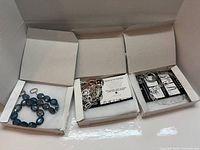 Three LOFTTAN necklace boxes opened showing each necklace