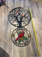 Both metal wall hangings shown together with tape measure for scale