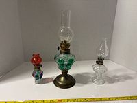 Three miniature oil lamps side by side showing relative sizes and colors