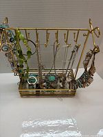 Front view of gold-tone jewelry stand holding assorted necklaces, bracelets, rings and earrings
