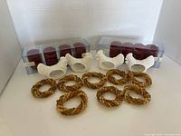 All napkin rings grouped: 4 ceramic roosters, 12 red beaded rings in boxes, 10 gold beaded rings