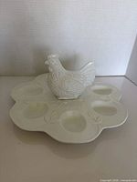Top view of white ceramic egg plate showing six wells and hen figurine