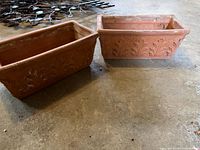 Two rectangular terracotta planters with embossed design placed on floor