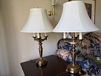 Both brass-tone table lamps with shades on side table