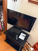Front view of 32-inch Panasonic TV on stand with remote and manual visible