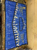 Full view of blue roll-up pouch opened with wrenches in labeled pockets