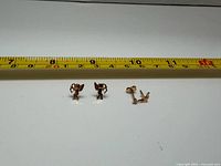Overview of three stud earrings beside ruler for scale