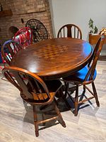 Round wooden table with chessboard inlay and four matching swivel chairs