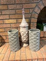 Front view of finial urn flanked by two gray planters