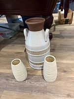 Front view of large handled jar with two small ribbed vases