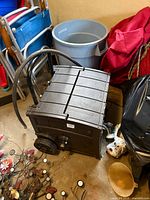 Overall view of Suncast hose reel cabinet on its side showing wheels, hose and surrounding items