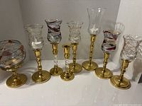 Eight assorted glass and brass candle holders lined up
