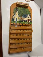Front view of calendar showing painted scene, month tile, weekday row and number tiles