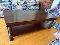 Full view of rectangular dark brown coffee table with lower shelf and turned legs