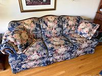 Front view of blue floral three-seat sofa with two matching throw pillows