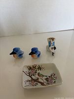 Front view: two bluebird shakers, bud vase, decorative dish