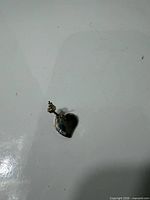 Heart charm and single earring on white surface