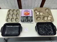 All six pieces laid out: two gold molded pans, two black motif pans, six mini molds (packaged)