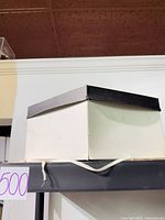 White cardboard hat box with black lid and tie