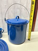 Lidded enamel pot with tape measure showing height