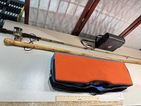 Full view of fishing rod with reel, croquet bag, binocular case and measuring stick