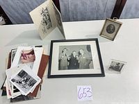 Lot overview showing framed photo, brass frame, acrylic holder, testimonial program and stack of loose photos