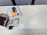 Accessories including charger, manuals, SD card, cable, clear pouch, plastic sheets on table