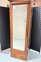 Full front view of mirrored armoire with bottom drawer
