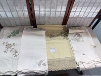 Group of folded ivory and cream embroidered tablecloths on table