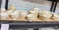 Teacups, cream soup bowls, saucers, plates, sugar bowl, creamer on shelf