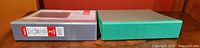 Grey Staples 2" view binder next to green binder, closed