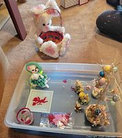 Plastic tote with assorted holiday decorations including Annalee doll, resin pieces, Valentine items