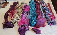 Top view of all eight scarves laid out showing colors and textures