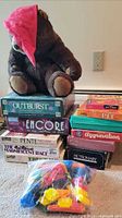 Overall lot with bear on top, showing stacks of boxed games and bag of pieces