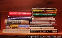 Full view of two stacks of assorted cookbooks on shelf
