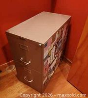 Full view of beige two-drawer file cabinet against red wall