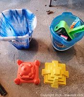 Sand buckets, shovel and molds on floor