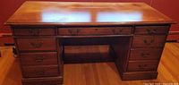 front view of solid wood executive pedestal desk showing all drawers and brass pulls