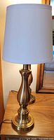 Single brass table lamp with white shade on wood surface