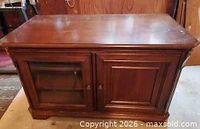 Front view of solid wood TV stand showing two doors, glass inset on left