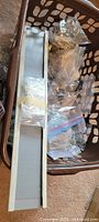 Laundry basket with boxed rail and multiple bags of curtain hardware