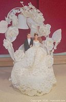 Front view of cake topper showing figures, lace base, floral arch