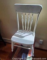 Front view of white wooden child's chair showing spindle back and seat
