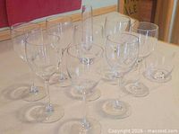 Group of clear stemmed wine glasses, one bud vase, and one stemless glass visible