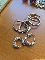 All three pairs of 14K yellow gold hoop earrings grouped together on surface