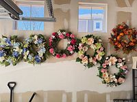Row of six artificial wreaths hung on wall