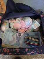 Open fabric case showing yarn skeins, crochet hooks in clear box, and storage boxes