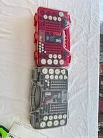 Two Battery Daddy organizer cases, red and clear gray, loaded with batteries and testers