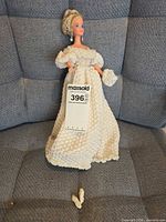 Full view of doll wearing gown, shoes placed in foreground