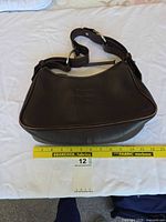 Front view of dark brown leather Dooney & Bourke hobo shoulder bag with measuring tape indicating 12 in width, silver-tone hardware visible